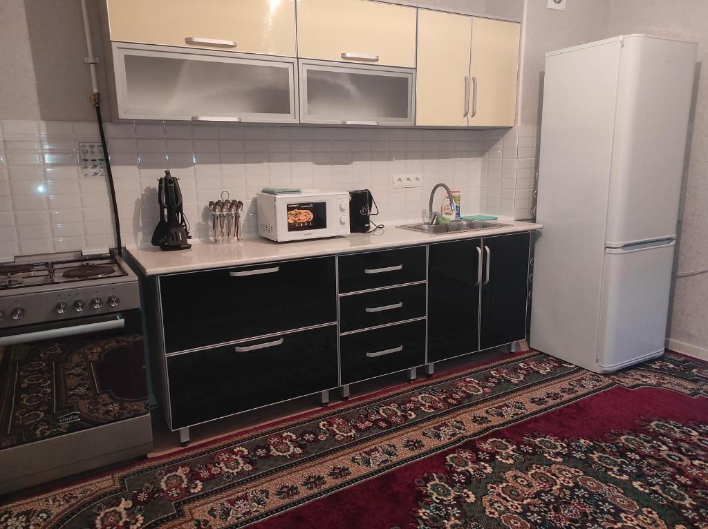 a kitchen with black cabinets and a white refrigerator at Светлая и уютная квартира в южной части Бишкека! in Bishkek