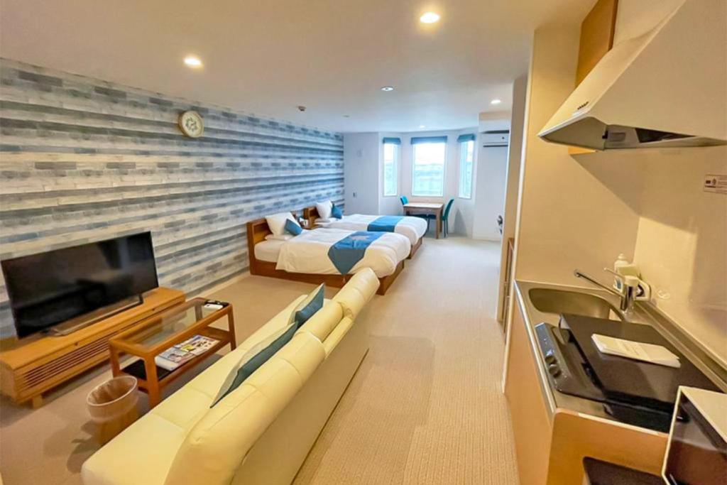 a living room with two beds and a tv at Hotel Santa Barbara Miyakojima Resort in Miyako-jima