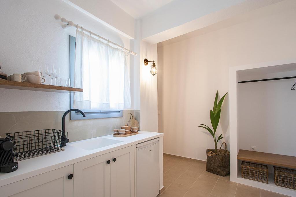une cuisine blanche avec un évier et une fenêtre dans l'établissement Paris Studios & Apartment, à Agia Paraskevi