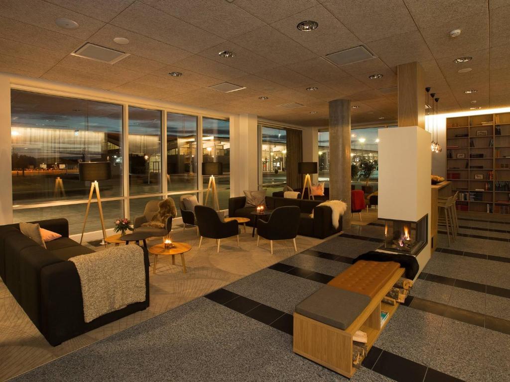 a lobby with couches and chairs and a fireplace at Aalborg Airport Hotel in Aalborg