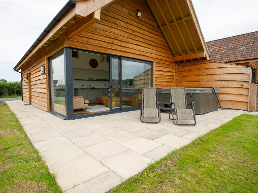 un patio con 2 sillas y una mesa en una casa en Starling Lodge, en Wedmore