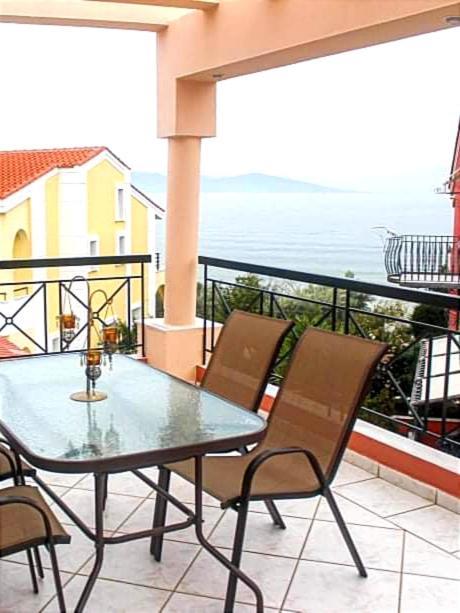 a table and chairs on a balcony with the ocean at Endless Blue Seaside in Paleo Tsifliki