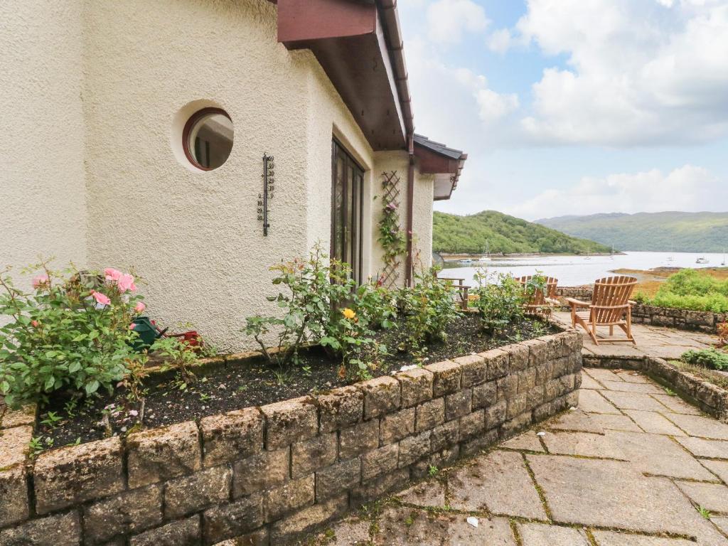 a house with a retaining wall and a table and chairs at Allt An Dorran in Acharacle