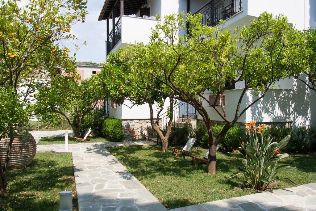 a garden with trees in front of a building at Paris Studios & Apartment in Agia Paraskevi