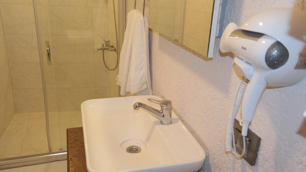 a bathroom with a sink and a shower with a hair dryer at ByAKKAN HOTEL in Bodrum City
