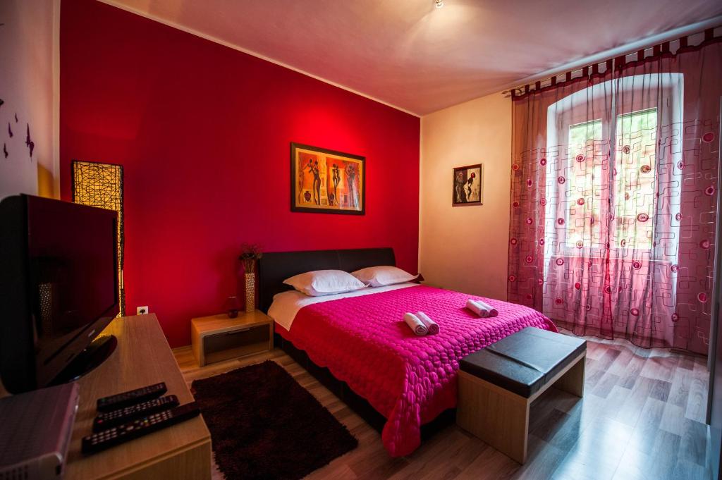 a red bedroom with a bed and a tv at Downtown Apartment Nora in Split