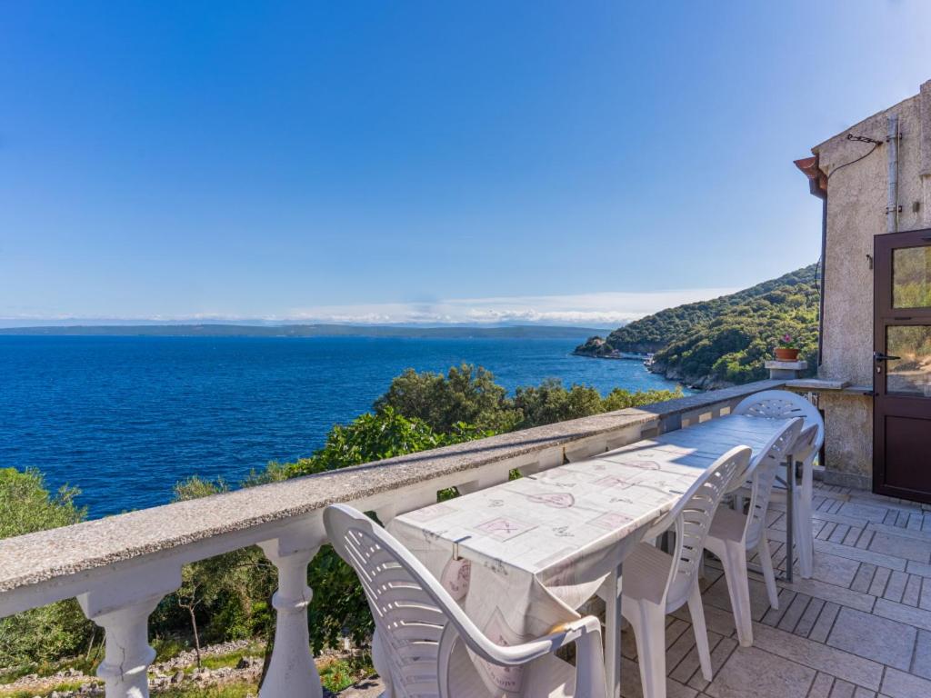a table and chairs on a balcony overlooking the ocean at Merag Sunrise Apartment in Cres