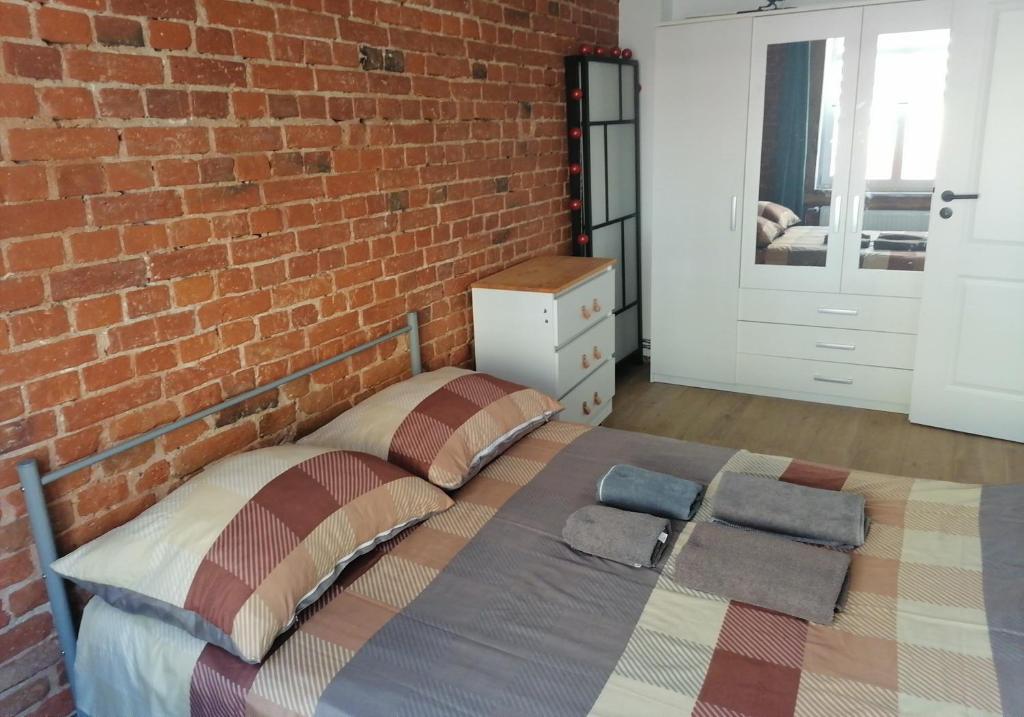 姆龍戈沃的住宿－Centrum Przy Promenadzie，一间卧室设有砖墙和一张床