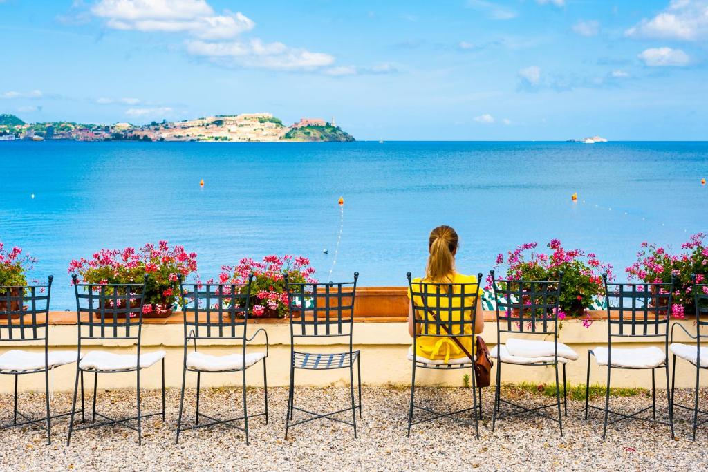 een vrouw in een stoel die naar de oceaan kijkt bij Hotel Villa Ottone in Portoferraio