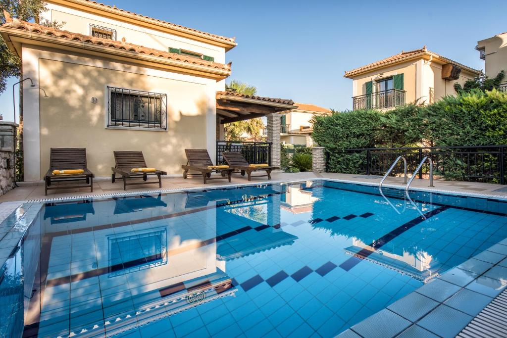 a swimming pool with two chairs next to a house at Kookis Village in Keri