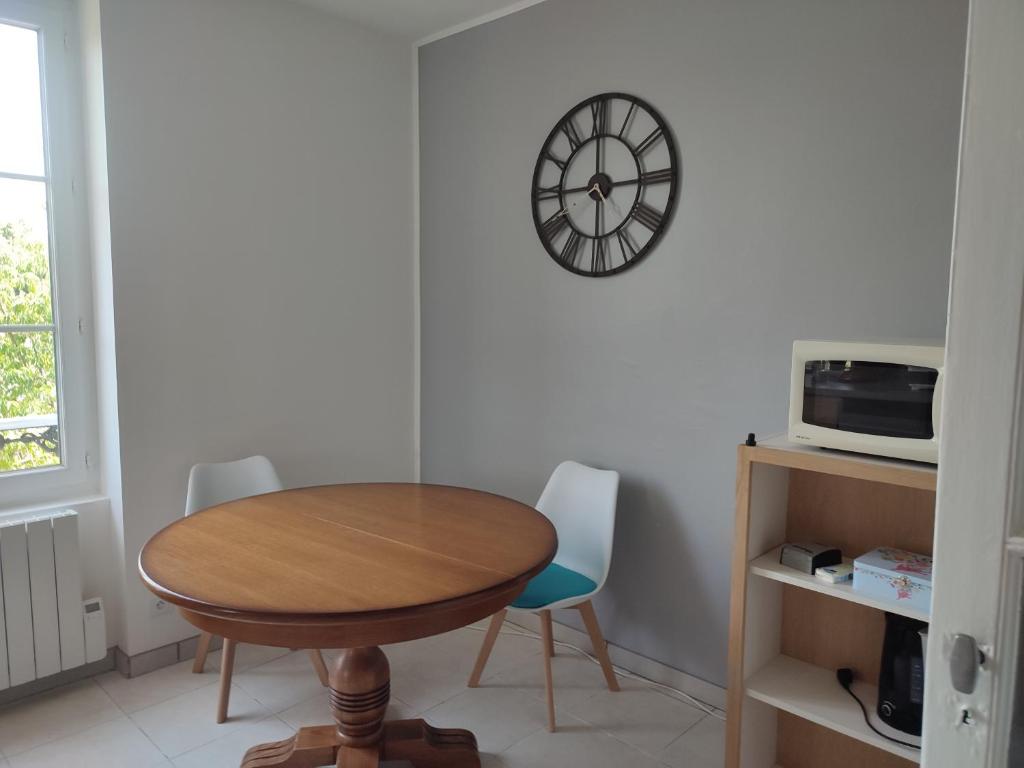 a dining room with a table and a clock on the wall at La maison fleurie 2 in Sainte-Geneviève-lès-Gasny