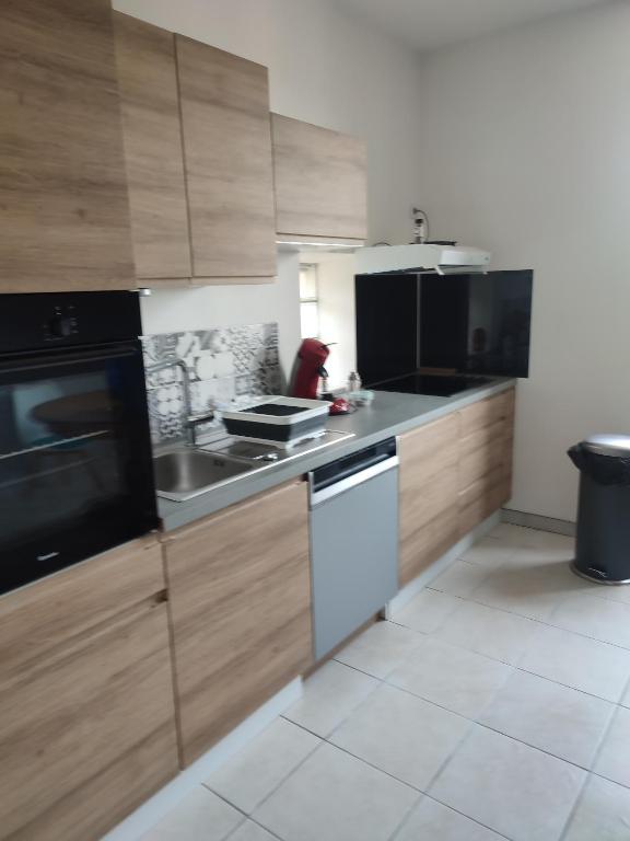 a kitchen with wooden cabinets and a stove top oven at La maison fleurie 2 in Sainte-Geneviève-lès-Gasny