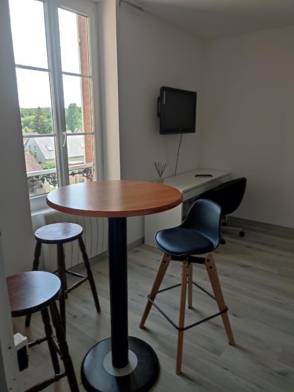 a room with a table and two chairs and a desk at La maison fleurie 2 in Sainte-Geneviève-lès-Gasny