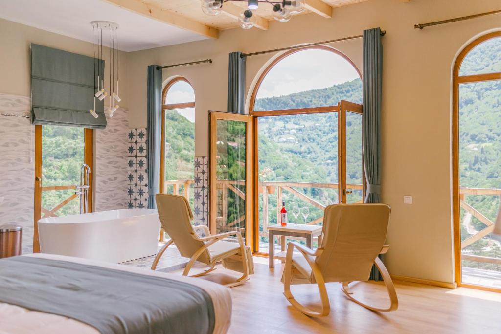 a bedroom with a bed and chairs and a tub at Hotel Chateau Iveri in Varjanisi