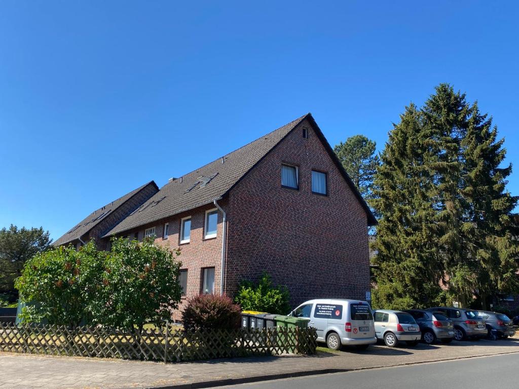 une maison en briques avec des voitures garées dans un parking dans l'établissement Stilvolle 2 Schlafzimmer Apartments Heidegarten, Osterheide, Zentrum, à Schneverdingen