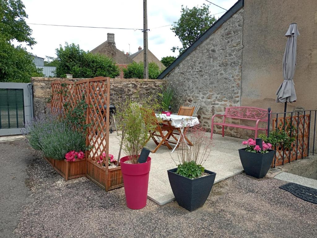 a patio with potted plants and a table and an umbrella at Appartement dans le Morvan 16 min de l'autoroute in Beauvilliers