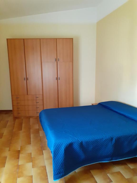 een slaapkamer met een blauw bed en houten kasten bij Ginepro in San Vito