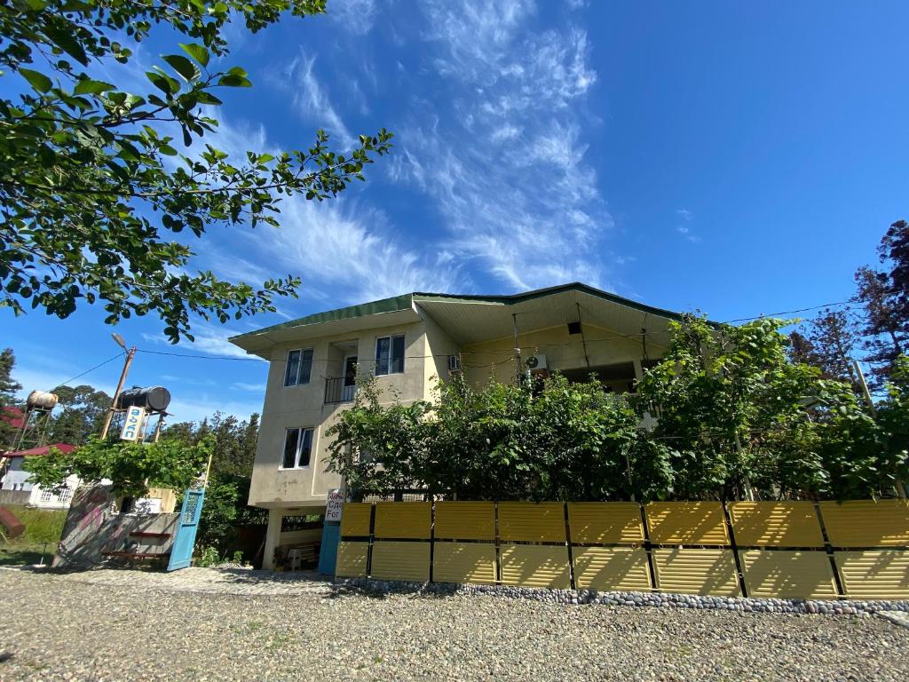 una casa con una valla amarilla delante de ella en Guest House Mari en Ureki