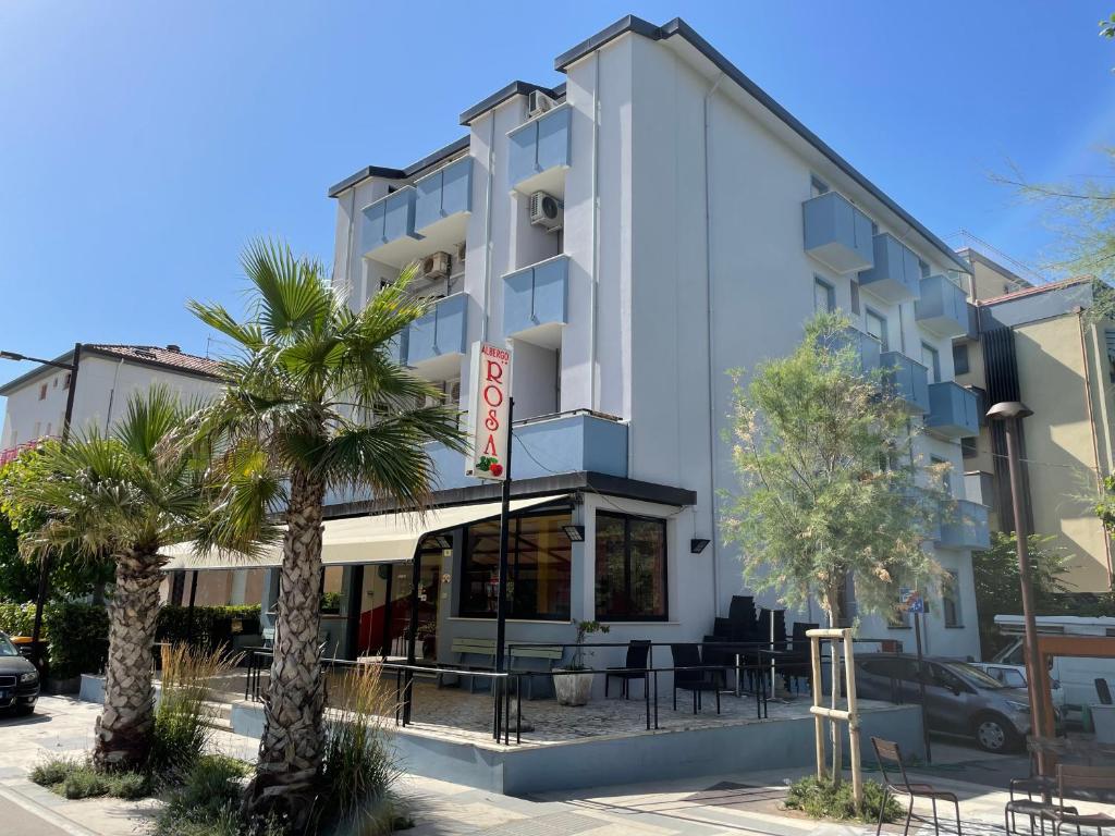 a building with palm trees in front of it at Hotel Rosa in Rimini