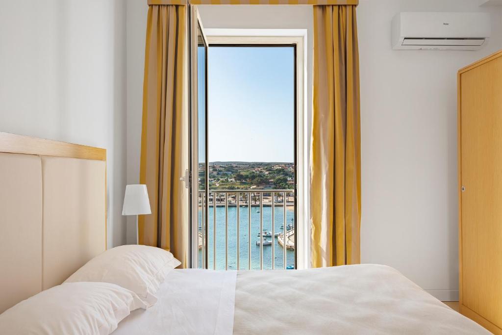 a bedroom with a bed and a view of the ocean at Hotel Vega in Lampedusa