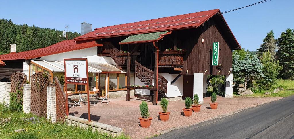 ein kleines Gebäude mit Pflanzen vor einer Straße in der Unterkunft Penzion U Dvou pánů in Pernink