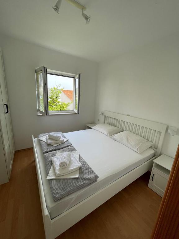 Un dormitorio blanco con una cama con toallas. en Apartments Vito, en Trogir