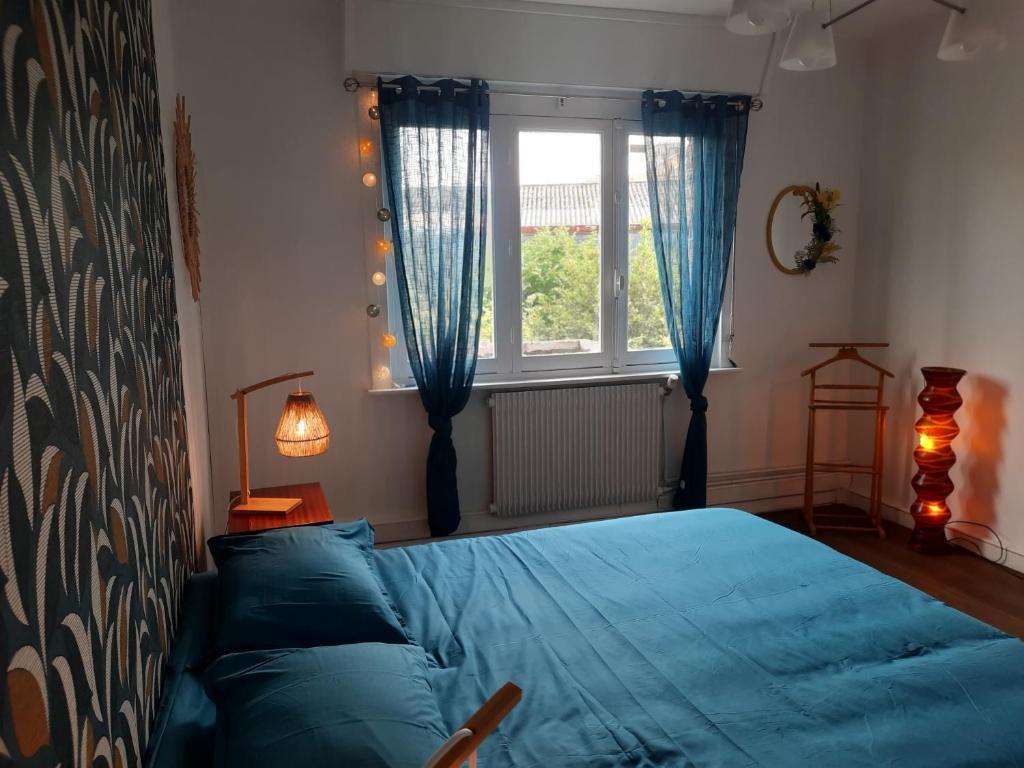 una camera con un letto blu e una finestra di Le soleil Dunkerquois a Dunkerque