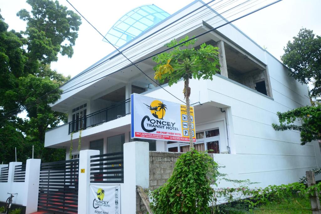 a white building with a sign in front of it at Concey Transit Hotel Airport view in Katunayaka