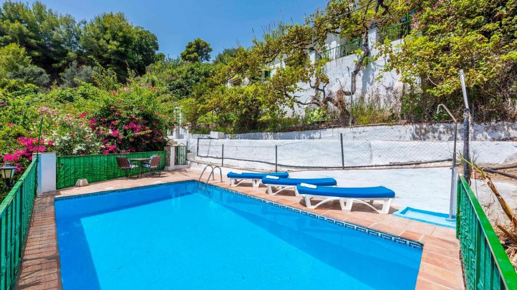 basen z niebieskimi stołami i ogrodzeniem w obiekcie Casa Maracuyá Nerja by Ruralidays w mieście Nerja