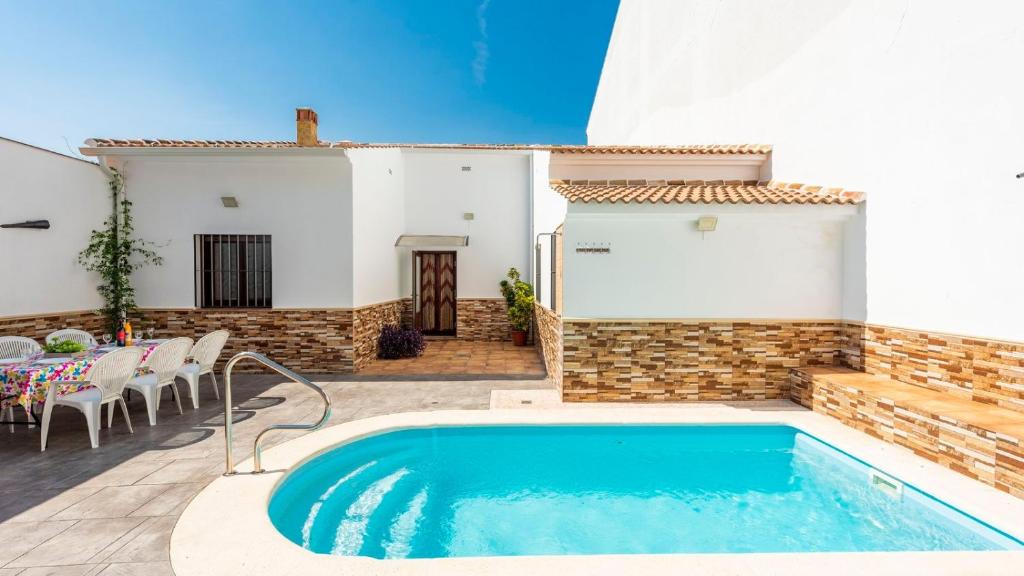 a pool in front of a house with a table and chairs at Casa Rural Sierra de las Nieves Yunquera by Ruralidays in Yunquera