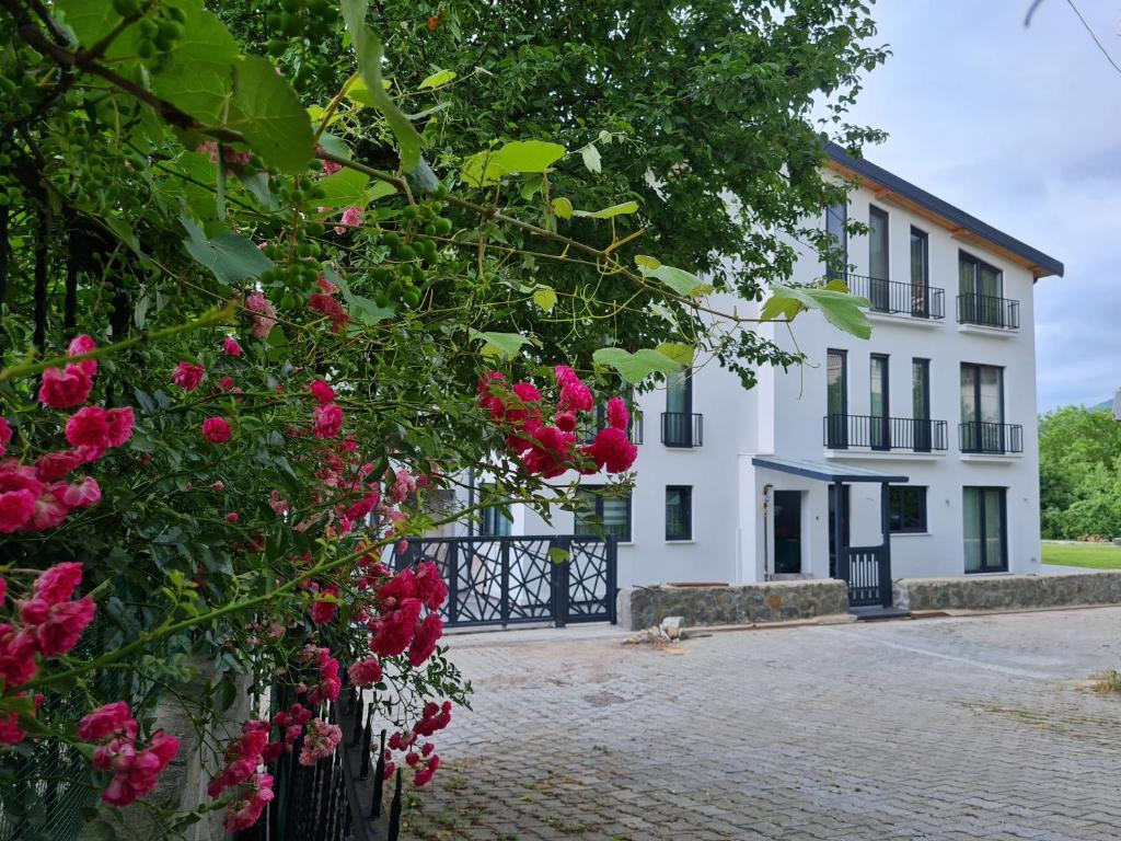 een wit gebouw met roze bloemen ervoor bij KD Apartments in Kartepe