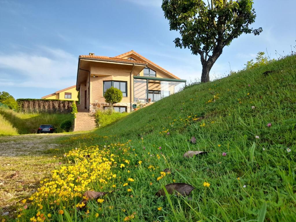 a house on the side of a hill with flowers at Chalet en Quintueles afueras de Gijón Asturias in Quintueles