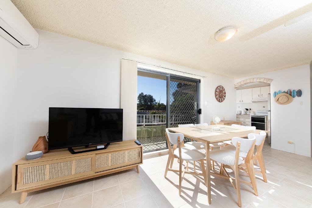 a dining room with a television and a table with chairs at Camelot Unit 12 in Forster