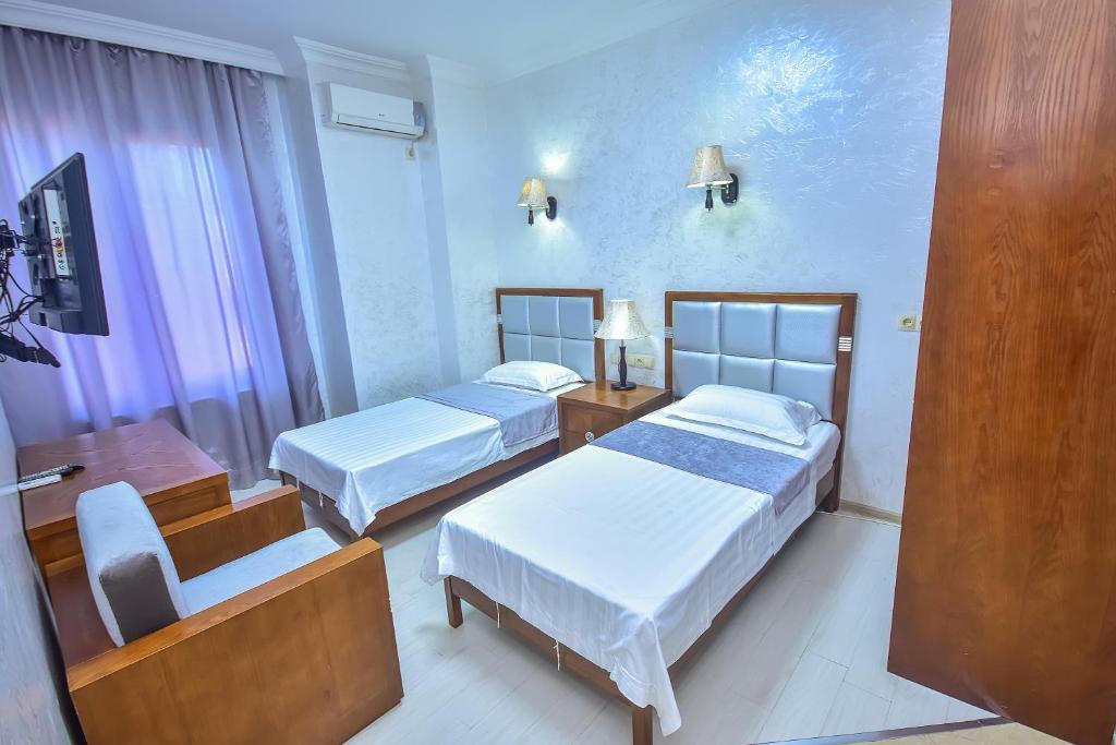 um quarto de hotel com duas camas e uma cadeira em Hotel Chveni Sakhli em Batumi