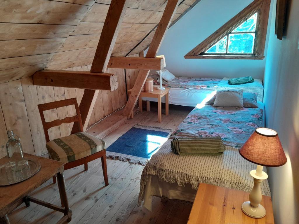 um quarto no sótão com uma cama, uma mesa e um candeeiro em Kurrebo em Urshult
