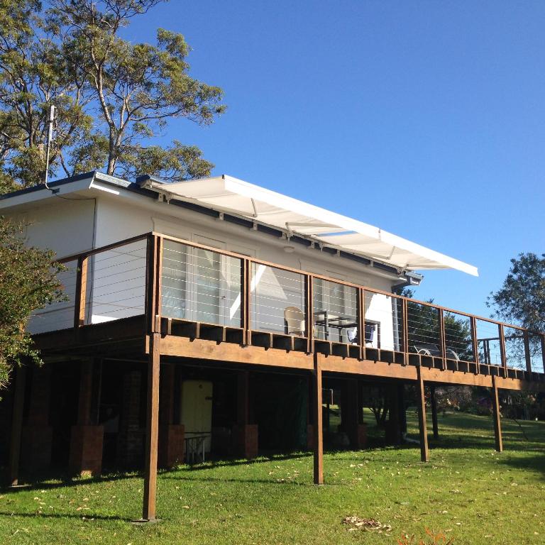 a house with a deck on the grass at Hyams Beach - A Secret Treasure in Hyams Beach