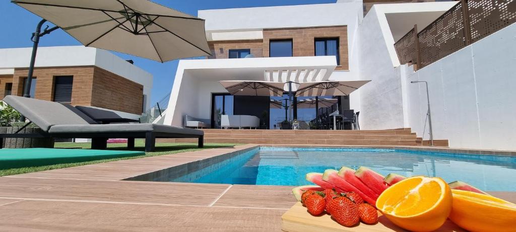 ein Pool mit Obst auf einem Tisch neben einem Haus in der Unterkunft VILLA VERAMAR in Finestrat