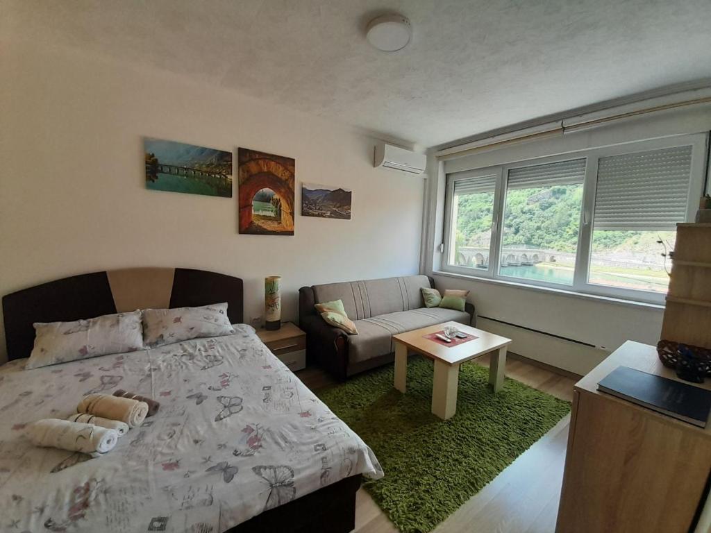 a bedroom with a bed and a couch and a table at Apartman Trg Višegrad in Višegrad