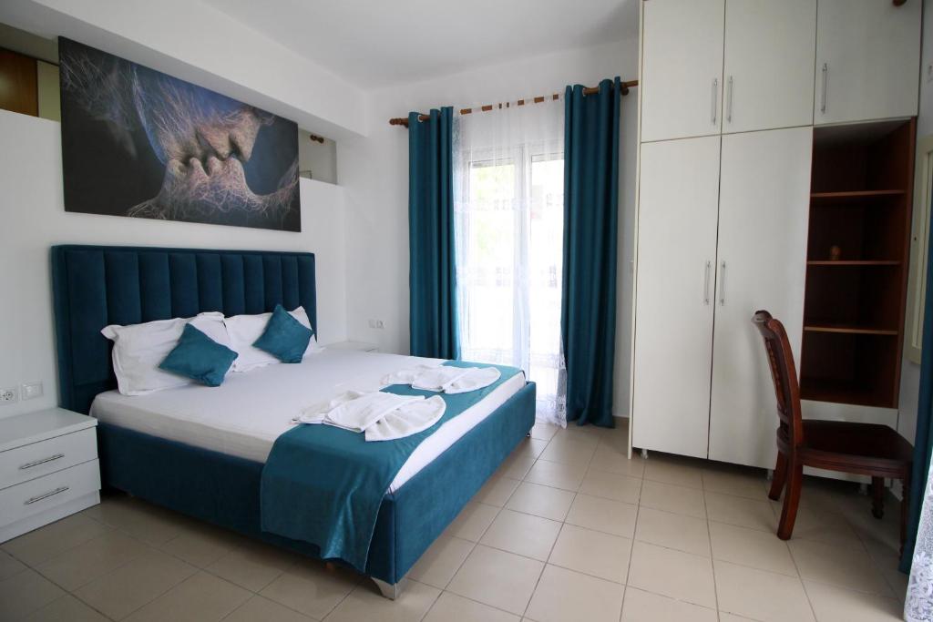 a bedroom with a bed with blue curtains and a chair at Hotel Vila Kapllani in Sarandë