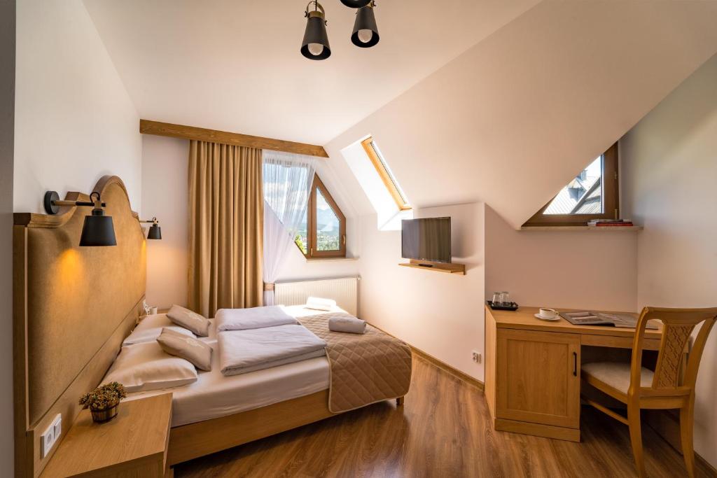 1 dormitorio con cama, escritorio y ventana en Miodowy Dworek en Bukowina Tatrzańska