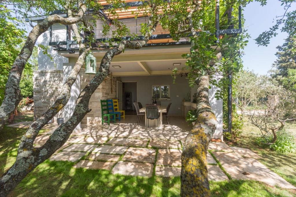 ein Haus mit einer Terrasse und Bäumen im Hof in der Unterkunft Peroj's Green Oasis - Holiday home in Peroj