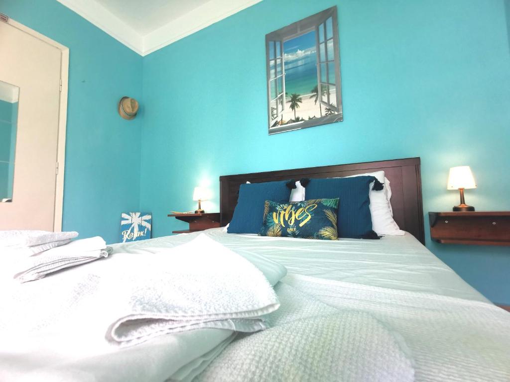 a blue bedroom with a bed with white sheets at Seaside BLISS in Agia Triada