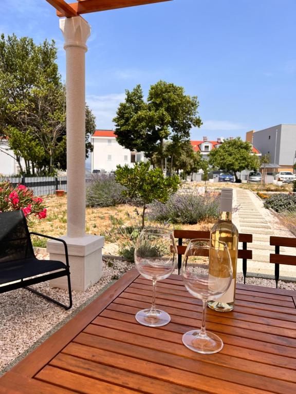 twee wijnglazen op een houten tafel op een patio bij Apartments Cvijet Mora Sreser in Sreser
