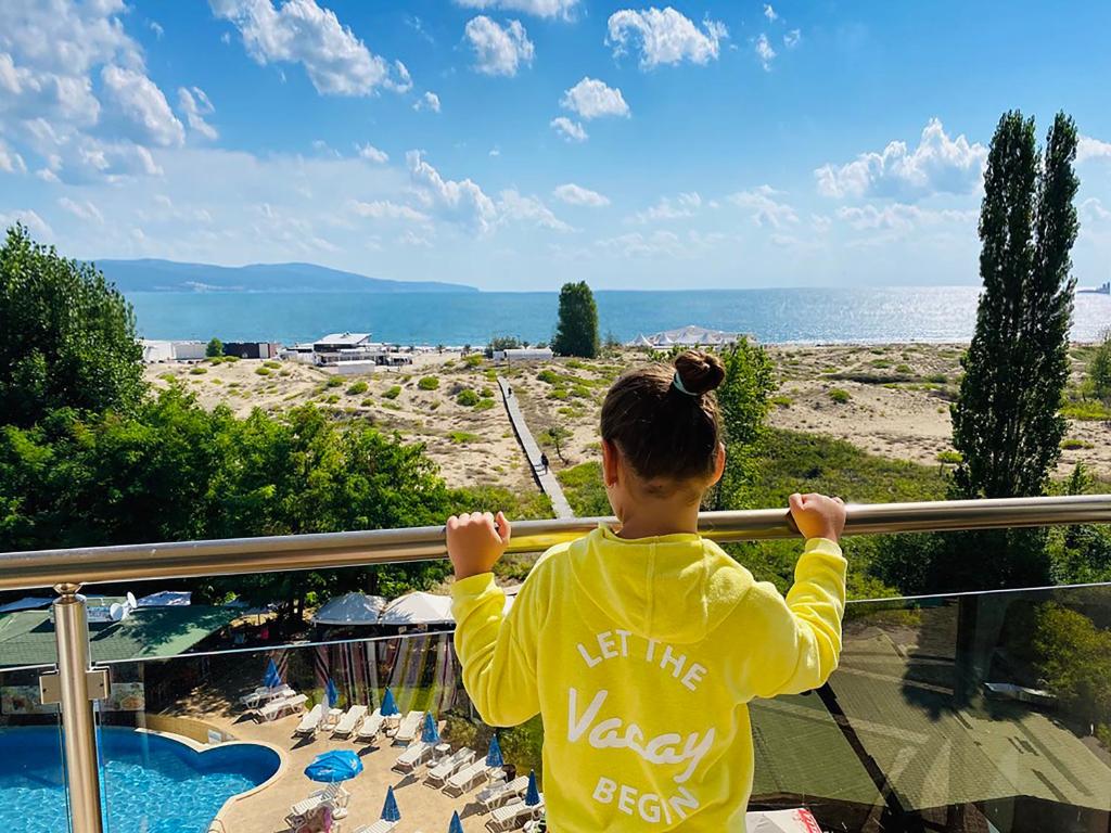 a woman standing on a balcony looking at the ocean at Sirena Hotel- ALL INCLUSIVE in Sunny Beach