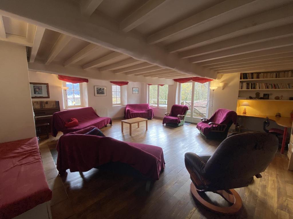 - un salon avec des canapés rouges et une table dans l'établissement Maison située au Val de Baubère, petite vallée à coté du village de Seix, à Seix