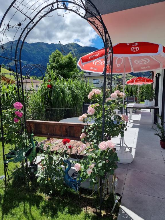 un jardín con un arco con flores y una sombrilla en Golf & Ski Appartements Mittersill Trausmuth Monika inkl Sommercard - Golfplatz 500 m entfernt, inkl Waschmaschine, Trockner, en Mittersill