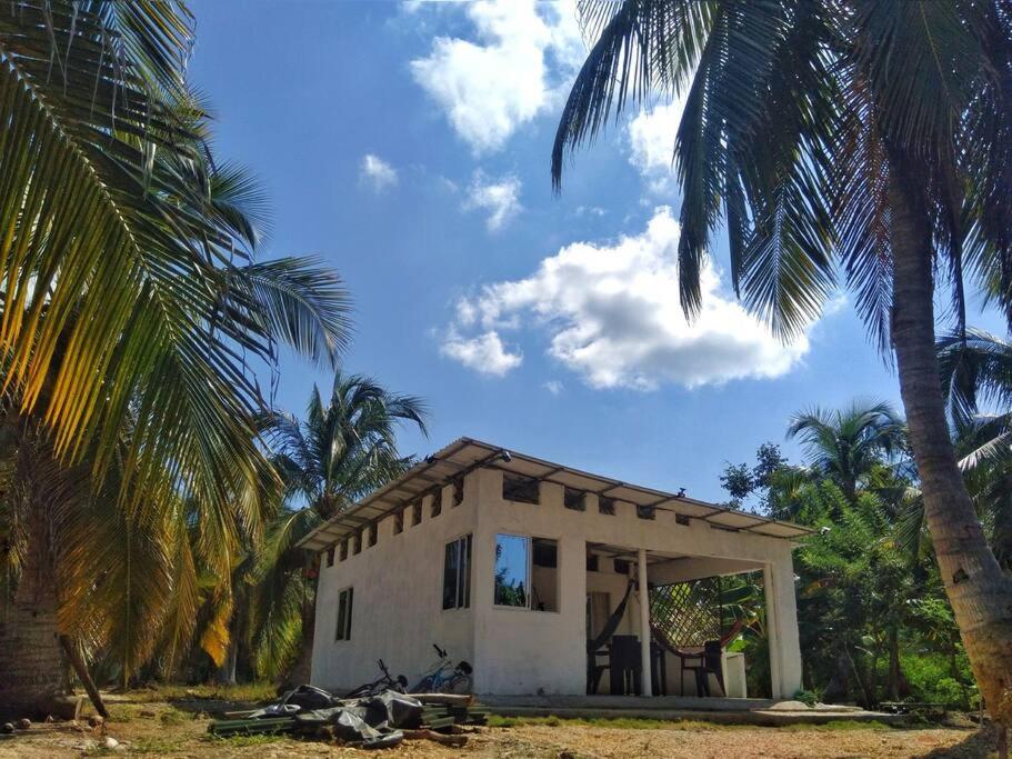 una pequeña casa con palmeras delante en Aldea Playa Real, en Moñitos