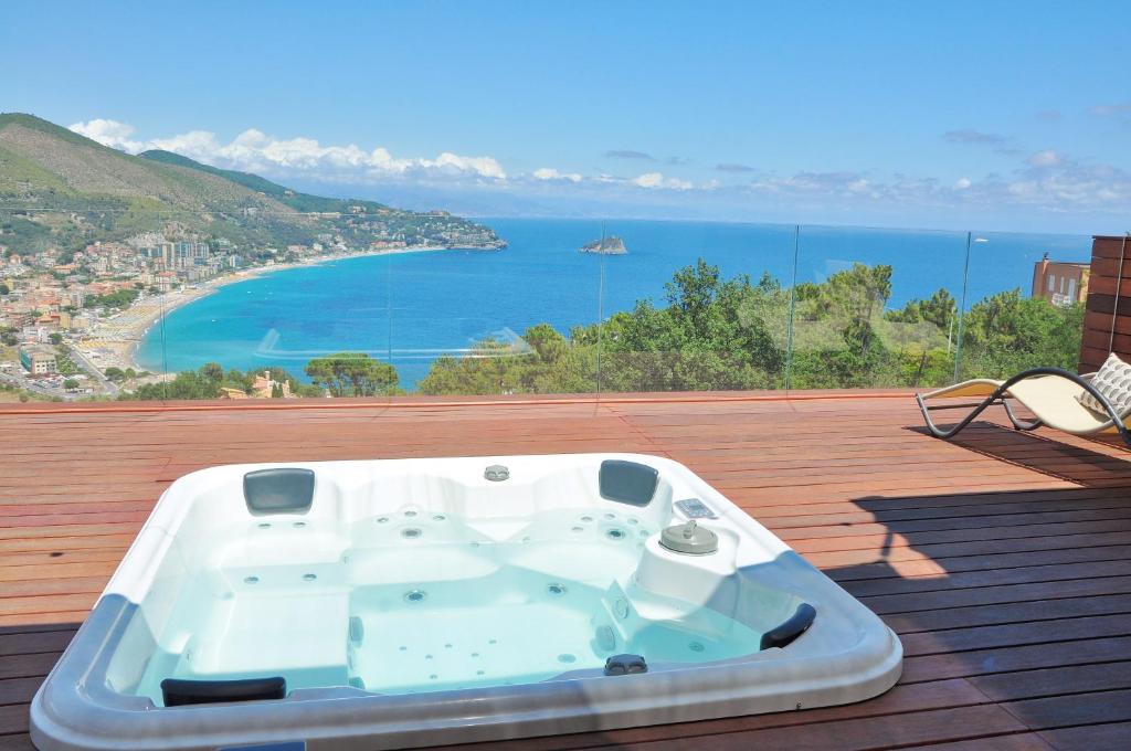 a bath tub sitting on a deck with a view of the ocean at Spettacolare vista isola Terrazza e idromassaggio in Noli