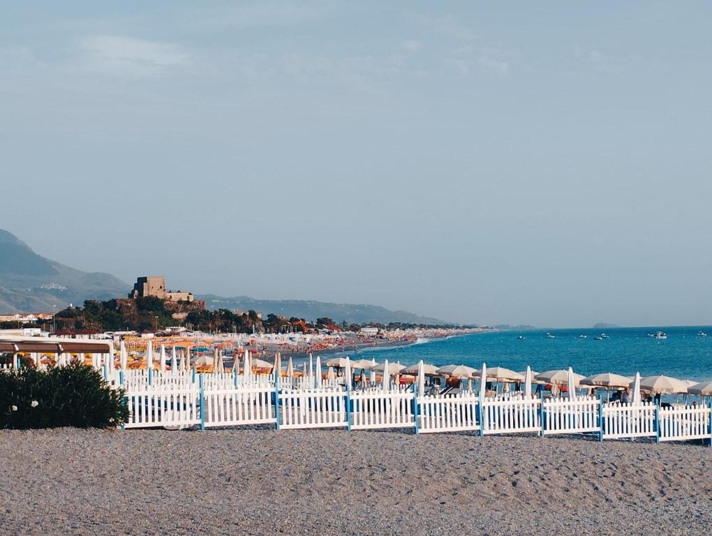 una playa con vallas y sombrillas blancas y el océano en Dimora degli Enotri en Scalea