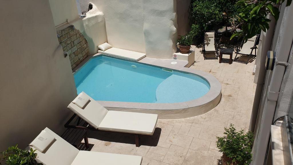 una vista aérea de una piscina con 2 sillas blancas en Casa Sofia Apt#1, en Spílion